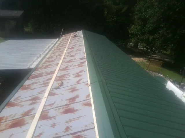 Old rusted panels beside newly installed green metal roofing — Wind Damage Roof Repair by Roofing Brothers in Holly Springs