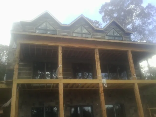 Dormers and porch framing on a large log home under construction — Roof Coating work by our crew in Holly Springs