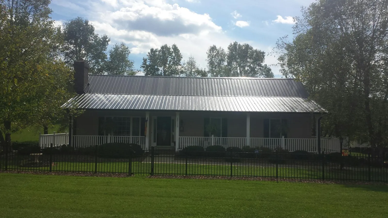 Gray metal roof on a brick ranch with a full width front porch — Gutter Guard Installation work by our crew in Holly Springs